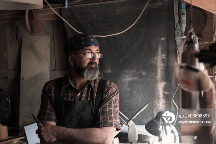 Spoon craft master in his workshop with handmade wooden products and tools