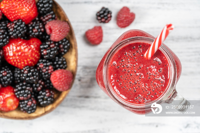 Fresh organic red smoothie in glass mug on white table, close up, top view. Refreshing summer fruit 