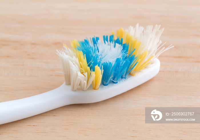 Old toothbrush on a wood counter top.