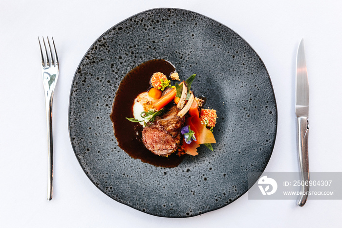 Modern French cuisine: Roasted Lamb neck & rack served with carrot, yellow curry served in black sto