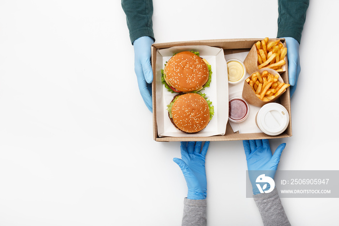 Fast food for two during coronavirus epidemic. Waiter hands in protective gloves gives box with burg