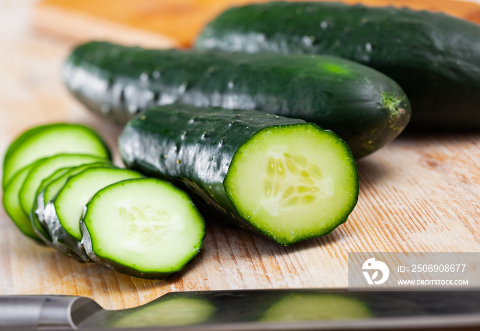 Close up of cut fresh green cucumbers on wooden background, nobody