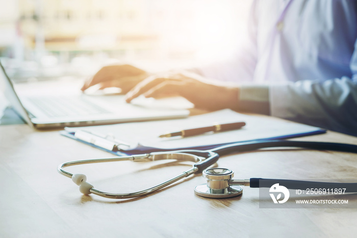 Doctor typing information on Laptop in Hospital office focus on Stethoscope