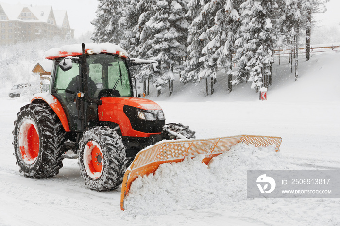 Red snowblower grader clears snow covered ski resort road in mountains or city street. Winter snowfl