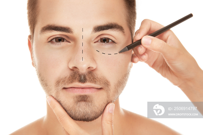 Surgeon drawing marks on male face against white background. Plastic surgery concept