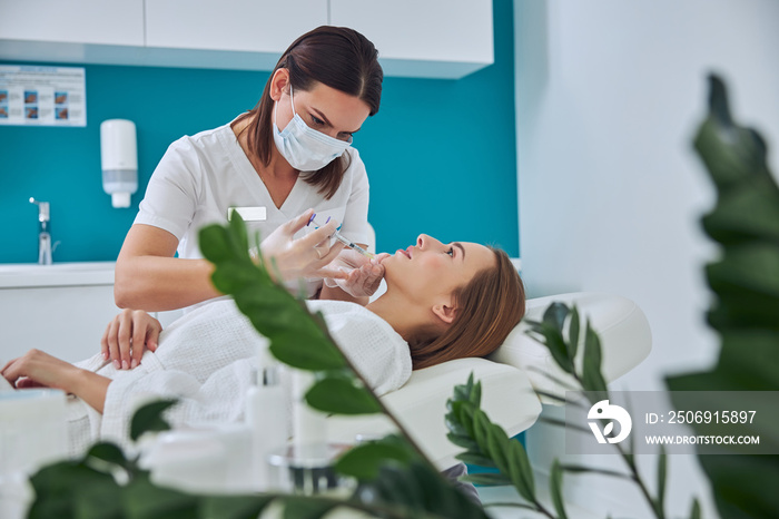 Elegant pretty female in white bathrobe receiving anti aging biorevitalization in cosmetic center