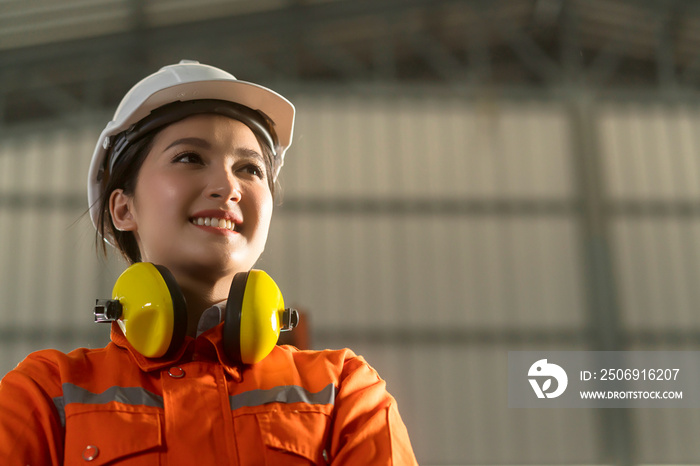 portrait of asian female engineer wearing uniform and saftey helmet standing confident and cheerful 