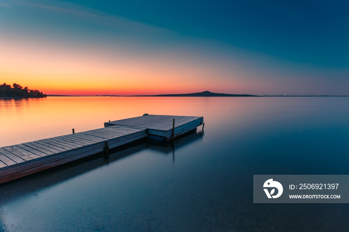 Wooden pier on a blue lake sunset and smooth reflection on water. Long exposure, Zerendi Lake, Kazak