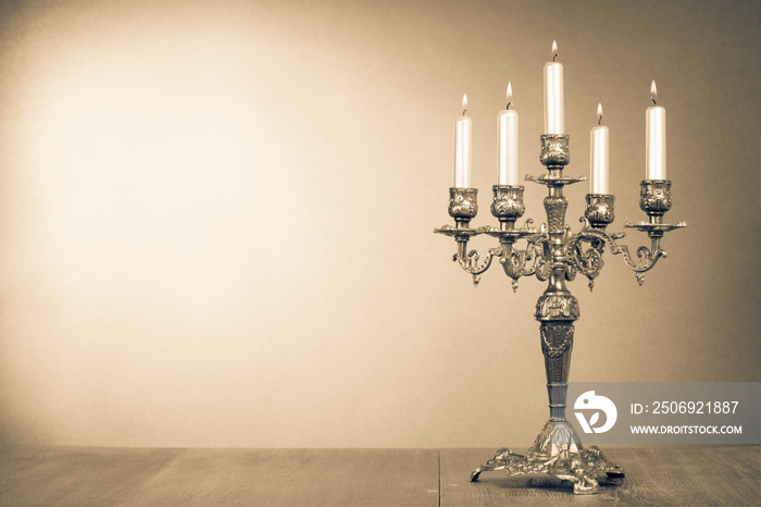 Old retro candlestick with five burning candles. Vintage style sepia photo