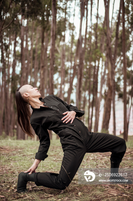 穿着工作服的时髦女性在森林的田野上练习当代舞蹈