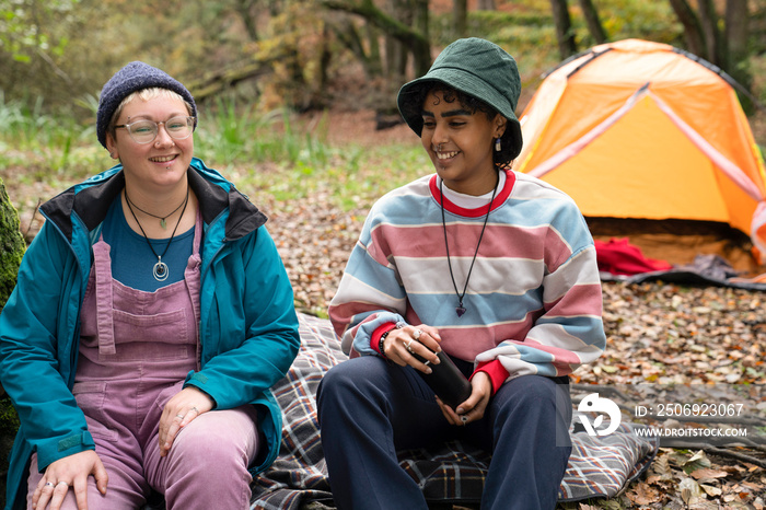 Smiling female friends camping in forest