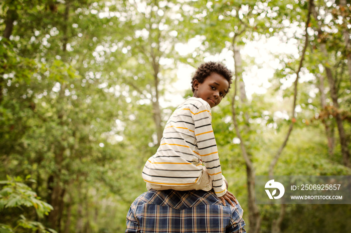 Portrait of boy sitting on his fathers shoulder