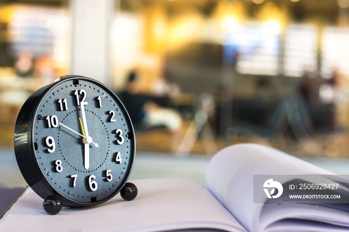 Notepad with pencil and clock on wood board background.using wallpaper for education, business photo