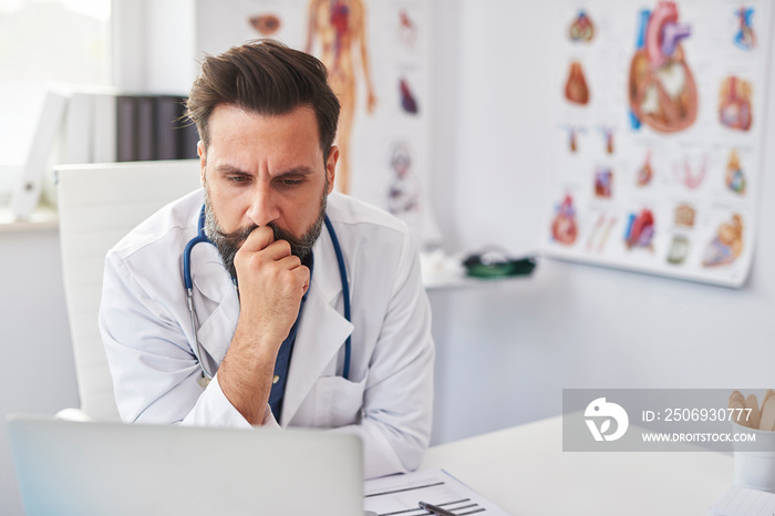 Busy doctor working with laptop in doctorâ€™s office