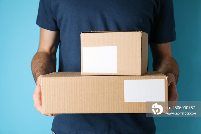 Delivery man hold blank boxes against blue background, space for text