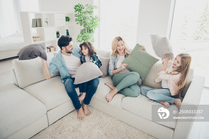 收养家庭的高角度照片四名成员在空闲时间玩枕头坐在沙发上生活