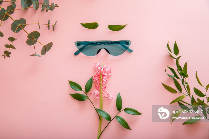 Creative concept female face made of sunglasses spring summer flowers on color summer background. Fe