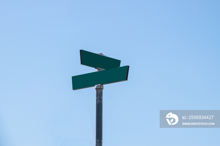 Blank green street signs on metal post with blue sky background