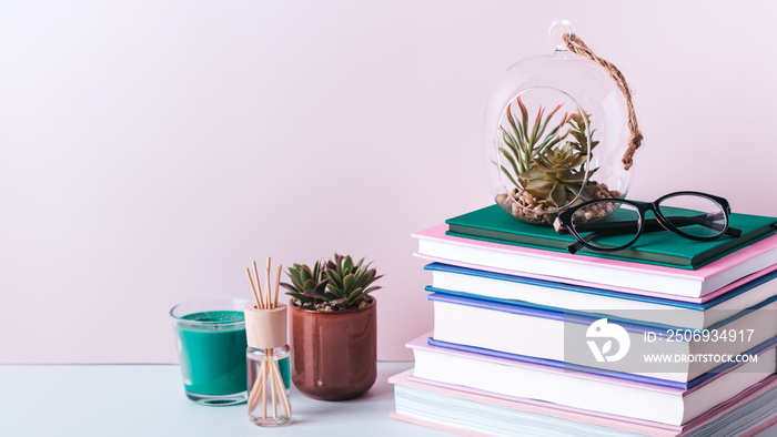 Books stack, eyeglasses, house plants succulents and fragrant candle and sticks. Background for Worl