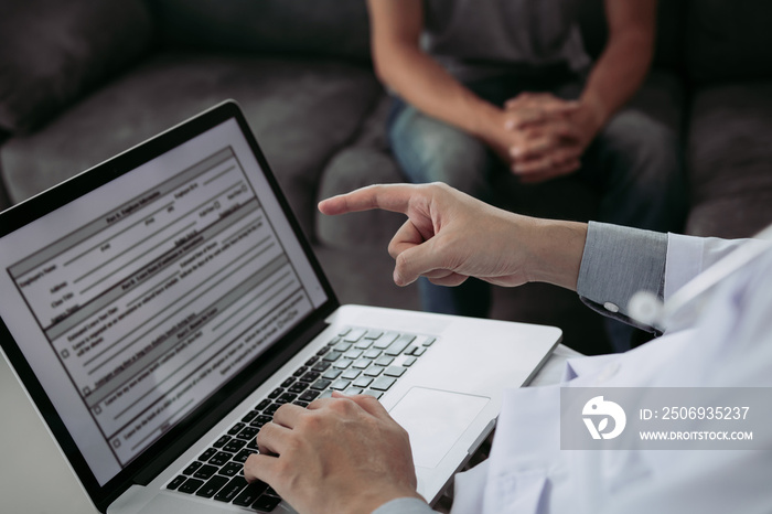 Doctor is using a laptop while typing the patient personal history record and giving advice about th