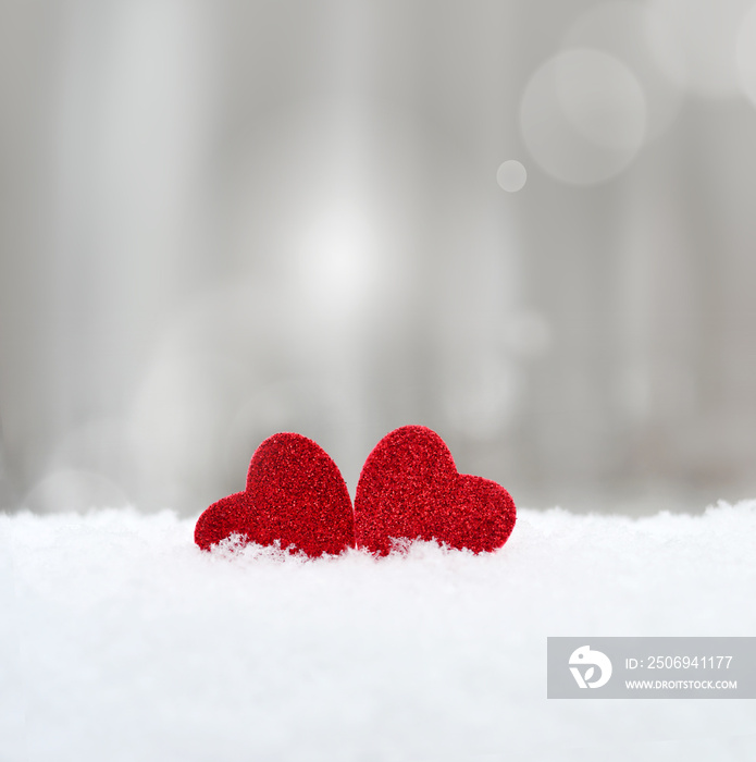 灰色背景下雪地里的两颗心。情人节概念。
