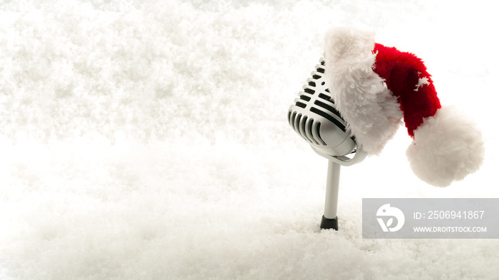 Carols and Christmas music concept with a microphone戴着圣诞老人帽隔离在白雪上