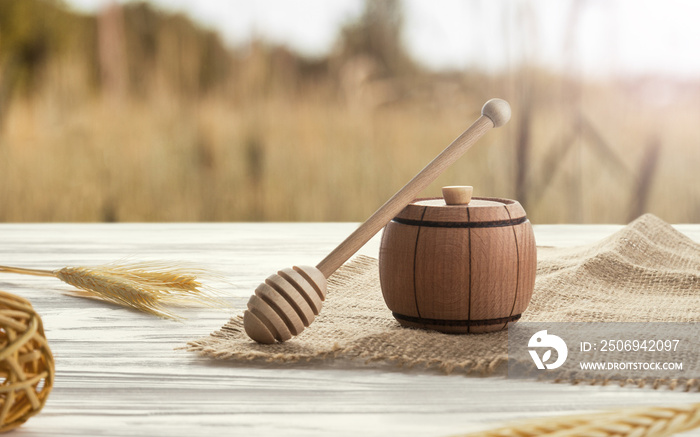 Wooden honey container and honey dipper on wooden table