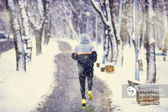 男子在雪地公园和寒冷的天气里慢跑。