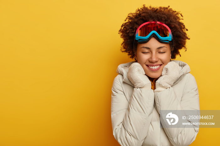 运动、滑雪场和单板滑雪的概念。快乐的非洲女人戴着滑雪面罩，戴着保暖的针织手套。