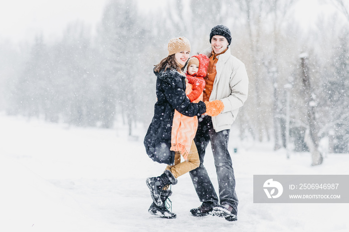 Cute family playing in the park in winter