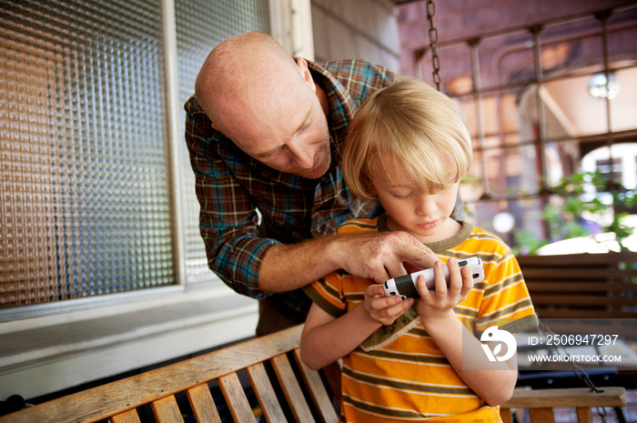 Father and son using mobile phone at home