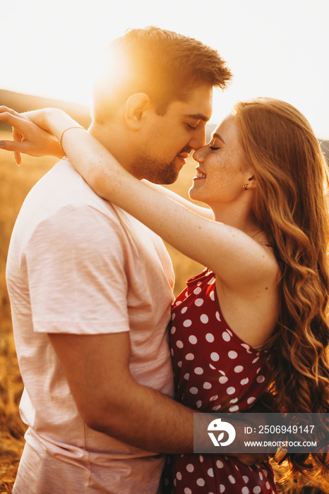 Side view of a couple smiling to each other on a sunny day. Man and woman in the summer in a wheat f