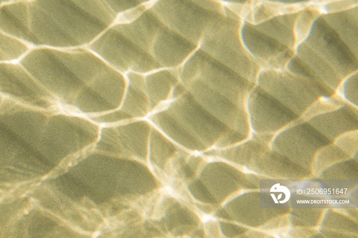 Detail sea bottom surface with natural wavy structure in sunlight. White reflections from sun in wat