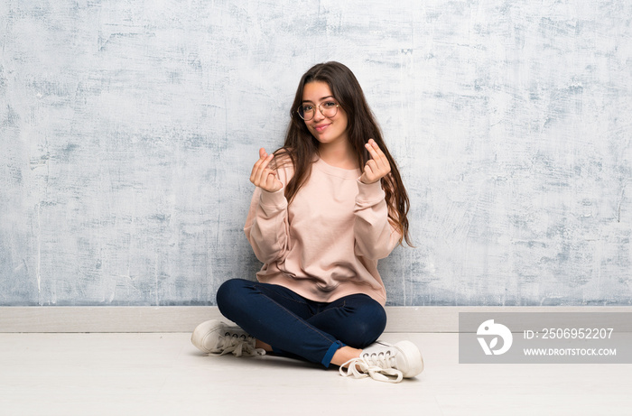 Teenager student girl studying in a table making money gesture