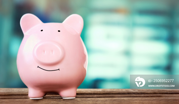 Piggy bank style money box on wooden table on bright background