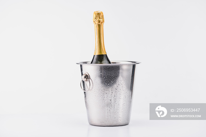 close up view of bottle of champagne in bucket on grey backdrop