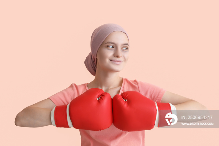 化疗后戴着拳击手套的女性，彩色背景。抗击癌症