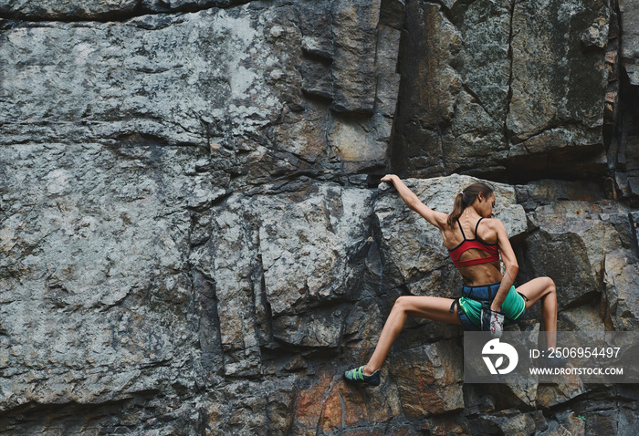 attractive slim muscular young woman rockclimber climbing on tough sport route, resting and chalking