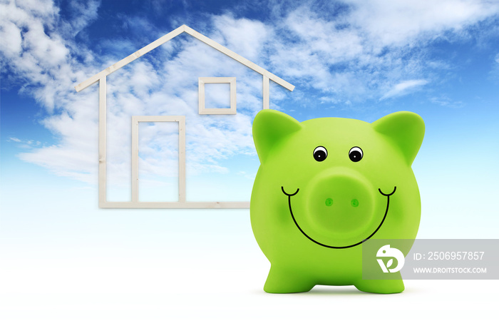 piggy bank with wood house shape isolated on blue sky background, green building and energy save con