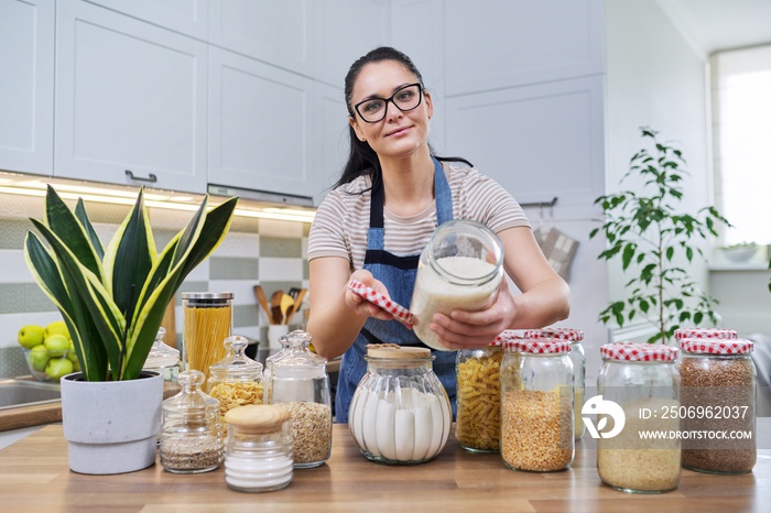 Smiling woman in the kitchen with jars of stored food.