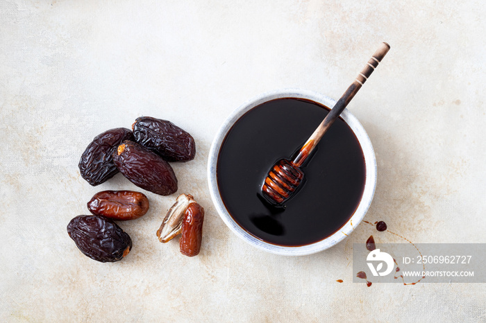 Natural date syrup in a bowl with whole dates in the background