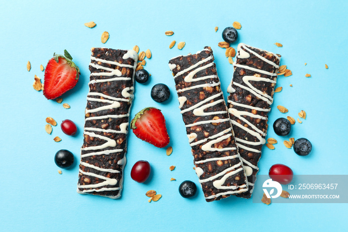 Tasty granola bars on blue background, top view