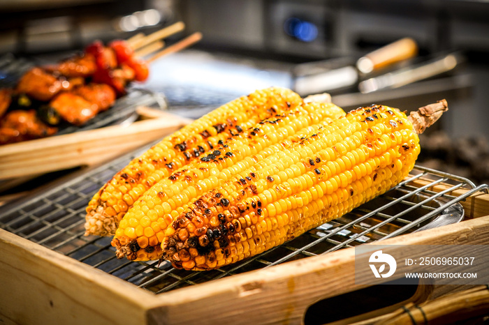 grilled corn on the grill with blur BBQ beside.