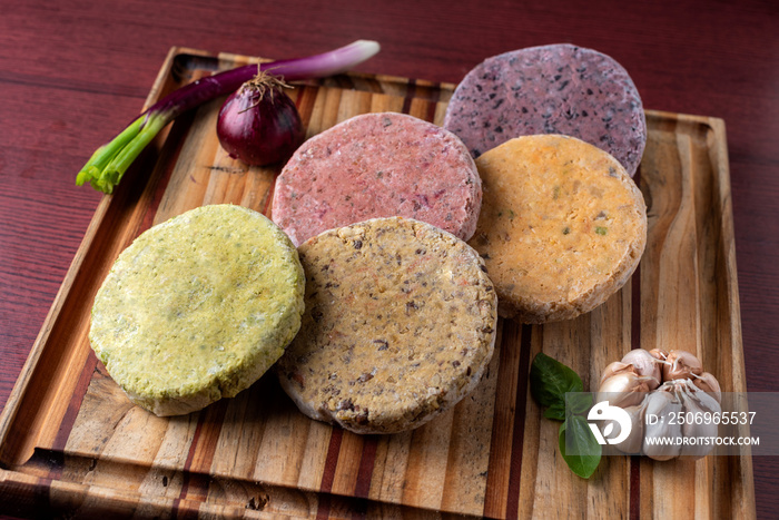 Vegan and vegetarian assorted legume and vegetable burgers of different colors on wooden board for a