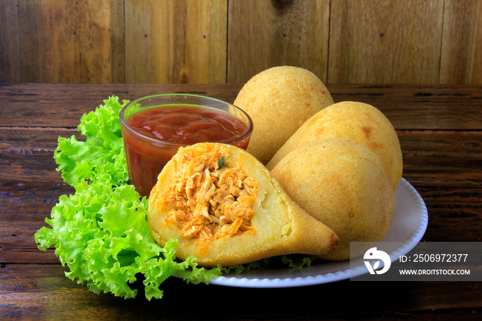 菜肴中的Coxinha，传统的巴西美食小吃，里面塞满了鸡肉，放在乡村的木头标签上