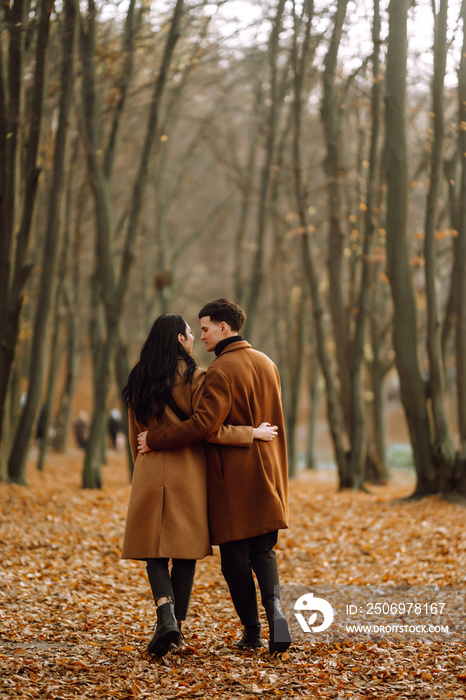 Young couple in love walking in the park on a autumn day. Enjoying time together. Stylish and loving