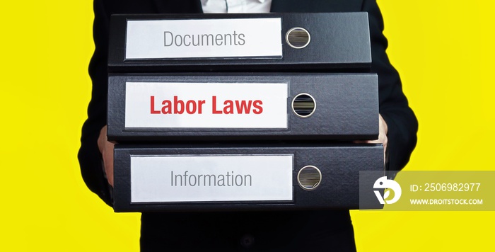 Labor Laws – finance/economics. Man carries a stack of 3 file folders. A folder has the label Labor 