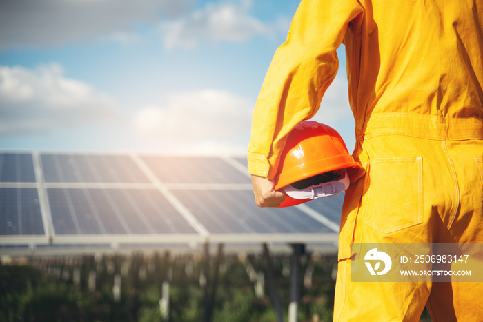 清洁能源概念。在太阳能电池板背面戴安全帽的电气工人或工程师