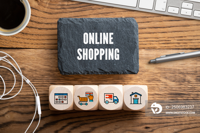 Schiefertafel mit Aufschrift  Online Shopping  und Würfel mit Einkauf-Symbolen am Computer-Arbeitspl