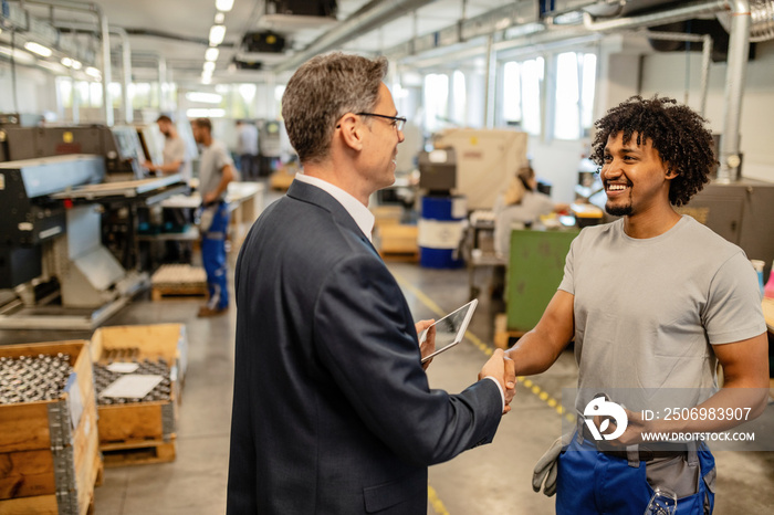 Happy African American worker greeting his manager in industrial building.